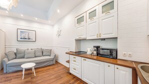 A modern kitchen with white cabinets, a wooden countertop, and a built-in microwave. - Apartamenty Sun & Snow Przy Monte Cassino (Sopot)