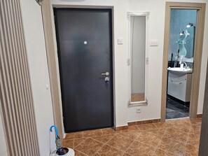 A room with a dark door, a mirror with an ornate frame, and a bathroom with a sink and toiletries.