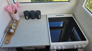 Una cocina con estufa, ventana y encimera con utensilios y recipientes.