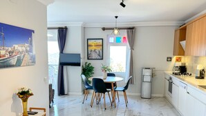 A modern kitchen with a dining area, marble flooring, and a large window with curtains. - Moonlight Apart Sea View (Kas)