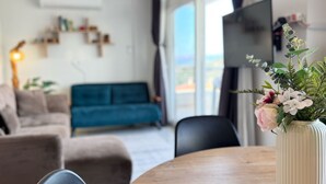 A modern living room with a blue sofa, a dining table with chairs, and a decorative vase with flowers. - Moonlight Apart Sea View (Kas)