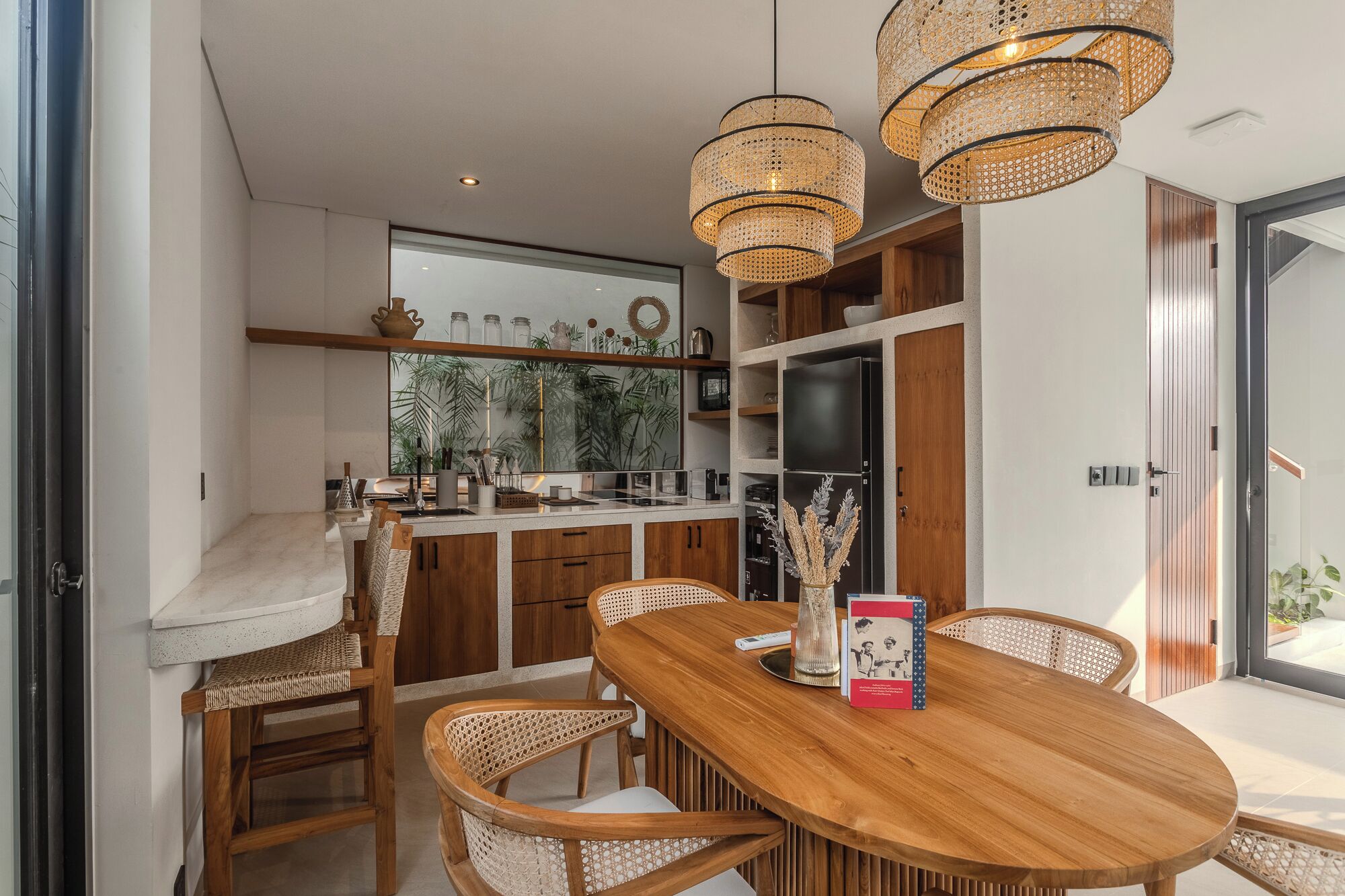 A modern kitchen with wooden cabinets, a large window, and a dining area with a wooden table and chairs.