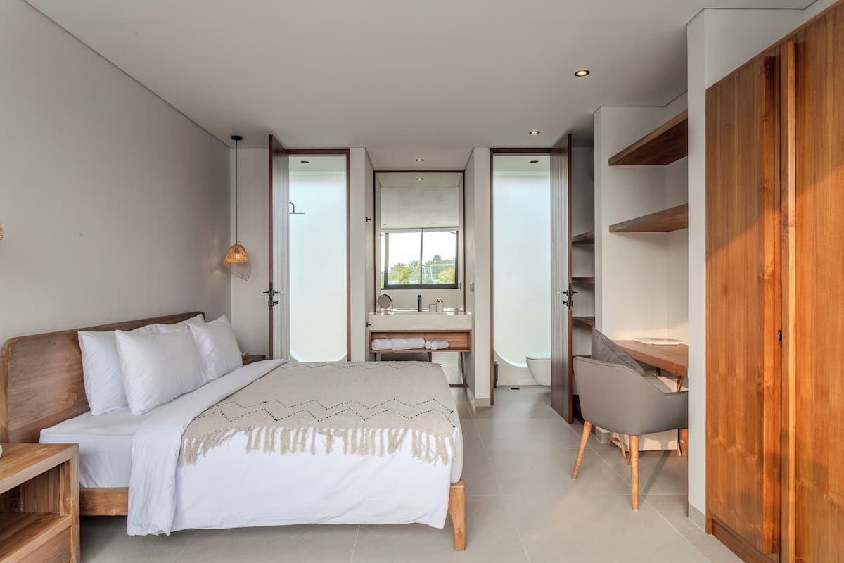 A modern bedroom with a bed, bedside tables, a desk, and a chair.