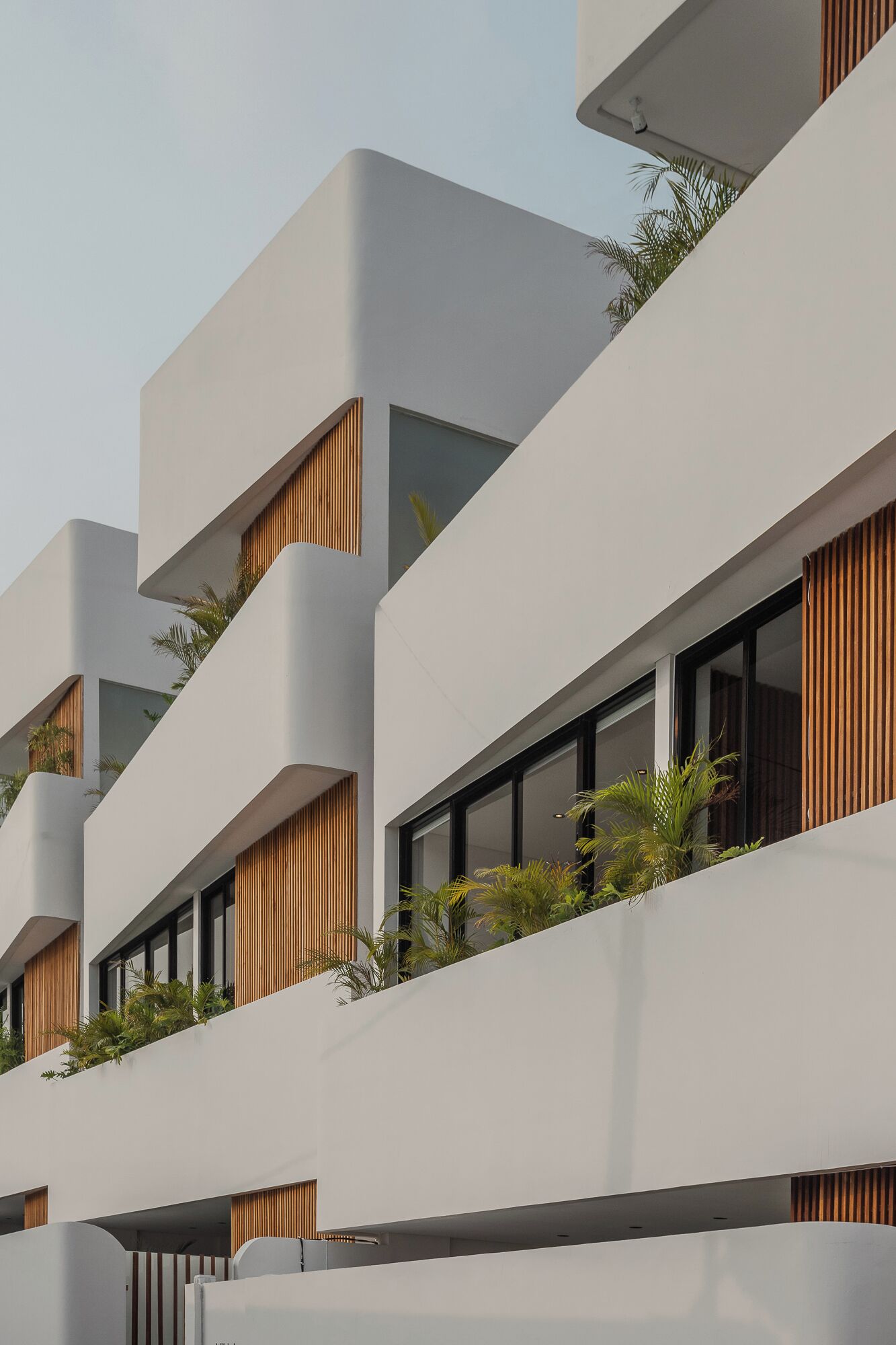Un edificio moderno de varios pisos con balcones, ventanas amplias y listones de madera.
