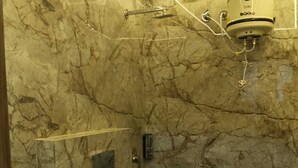 Een badkamer met een marmeren wand, een toilet, een wastafel en een douche.