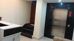 Een moderne lobby met een receptiebalie, een trap en een lift.