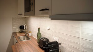 A kitchen with a wooden countertop, a sink, a toaster, and a bottle of olive oil.