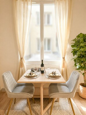 A dining table with two chairs, a bottle of wine, and glasses. - 5498 Au Maire (Paris)