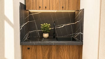 Una cocina con salpicadero de mármol negro, armarios de madera y un lavamanos negro.