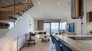 A modern living area with a sofa, coffee table, and bar area. There is a staircase with a glass railing and a large window offering a view.