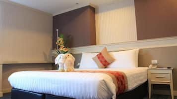 A hotel room with a large bed, a nightstand, a telephone, and a decorative plant.