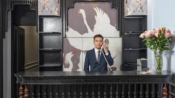 A reception desk with a large decorative panel featuring a swan, a telephone, and a vase with flowers.