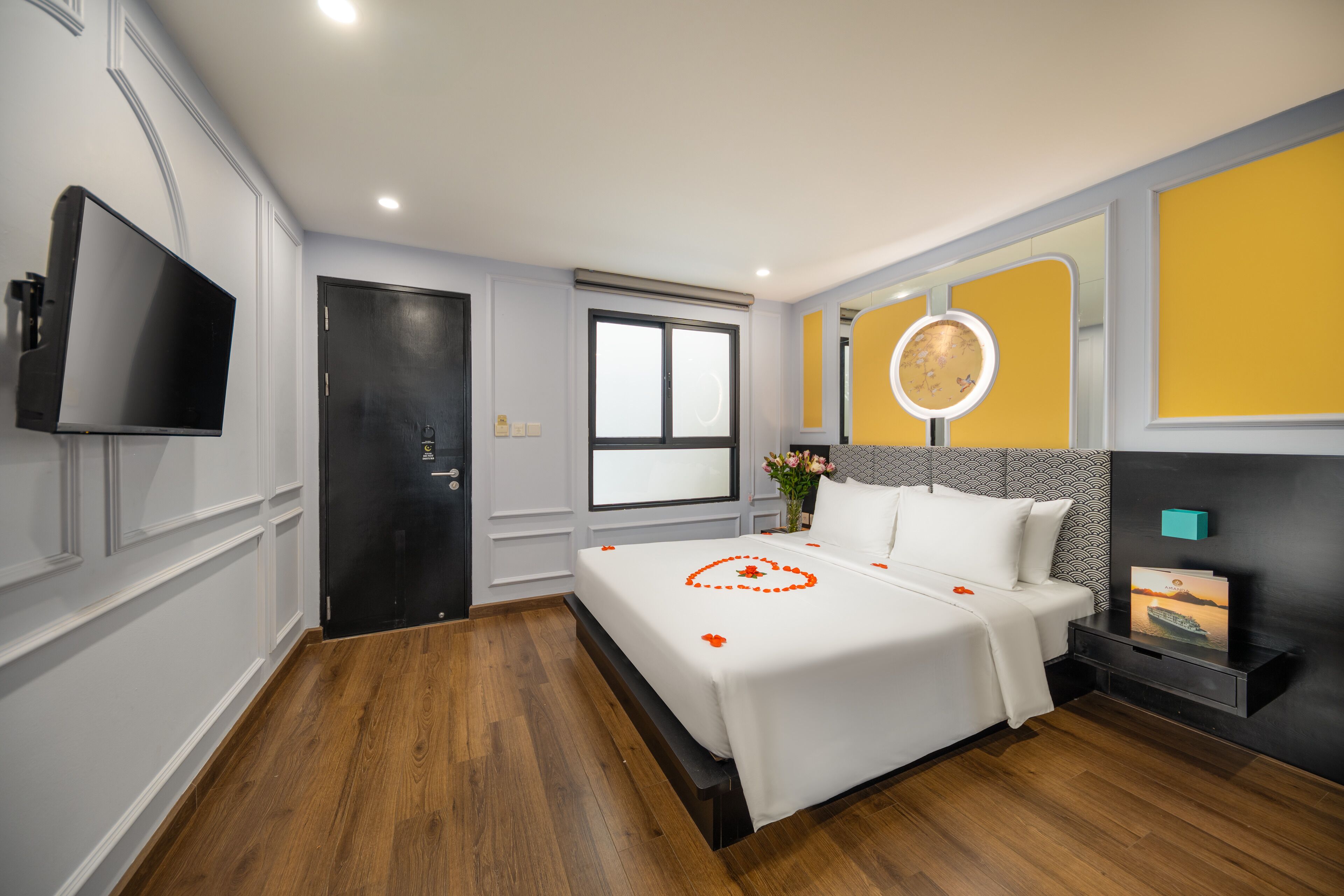 Una camera d'albergo con un letto, una TV, un comodino, uno specchio e una finestra.