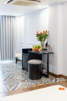 Ein Hotelzimmer mit Bett, Schreibtisch, Blumenvase, Fahrrad und Minibar.