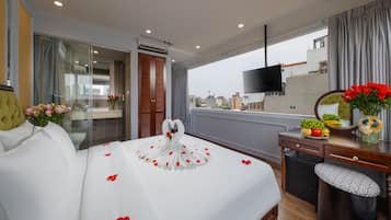 Ein Hotelzimmer mit Bett, Schreibtisch, Sessel, Fernseher und Blick auf die Stadt.