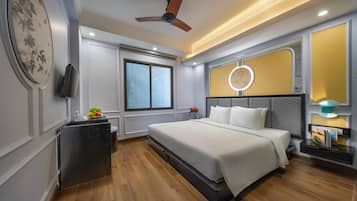 A modern bedroom with a bed, a ceiling fan, a TV, a bedside table, a nightstand, and a window.