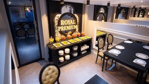 Un espace repas avec un buffet, une enseigne indiquant « ROYAL PREMIUM » et une table dressée pour six personnes.