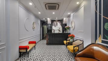 A hallway with a patterned floor, a reception desk, a bench, and a leather couch.
