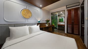 Une chambre d’hôtel avec un grand lit, un bureau, un miroir et une armoire.