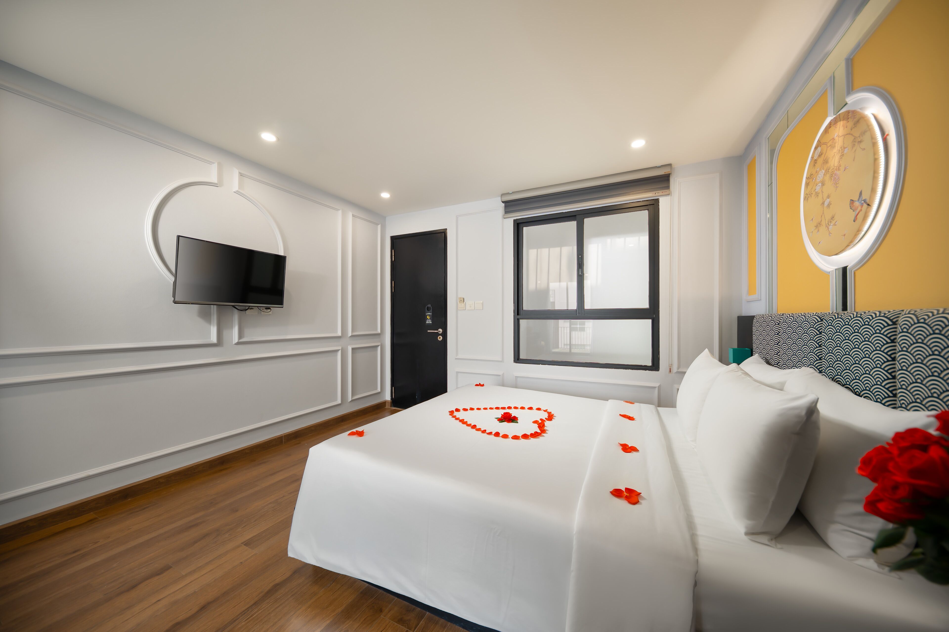 Een hotelkamer met een bed, een aan de muur bevestigde televisie, een raam en een klok aan de muur.