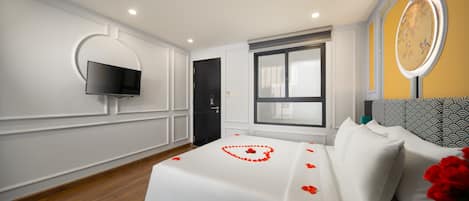 Habitación de hotel con una cama, televisión instalada en la pared, ventana y un reloj en la pared.
