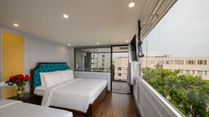 Une chambre d’hôtel avec deux lits, une grande fenêtre et un balcon.