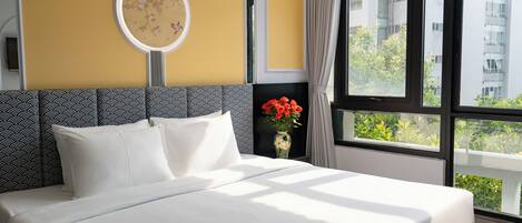 Habitación de hotel con una cama grande, un espejo redondo en la pared y vistas a zonas verdes.