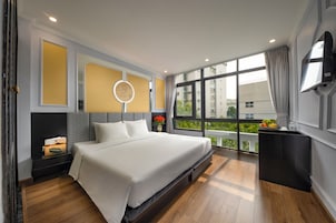 Un dormitorio moderno con una cama grande, una mesita de noche con espejo y un televisor en la pared.