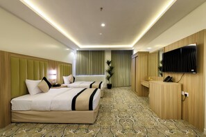 A hotel room with two beds, a desk, a mirror, and a television.