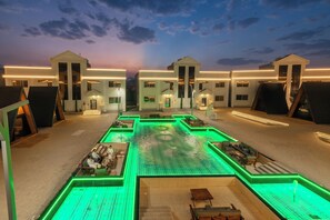 A modern hotel with a central courtyard, multiple entry points, and a pool area with green lighting.