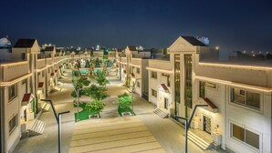 Een hotel binnenplaats met meerdere gebouwen, een fontein in het midden en een goed verlichte looppad.