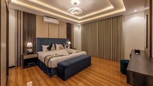 Een moderne hotelkamer met een groot bed, nachtkastjes, een bureau en een plafondlamp.