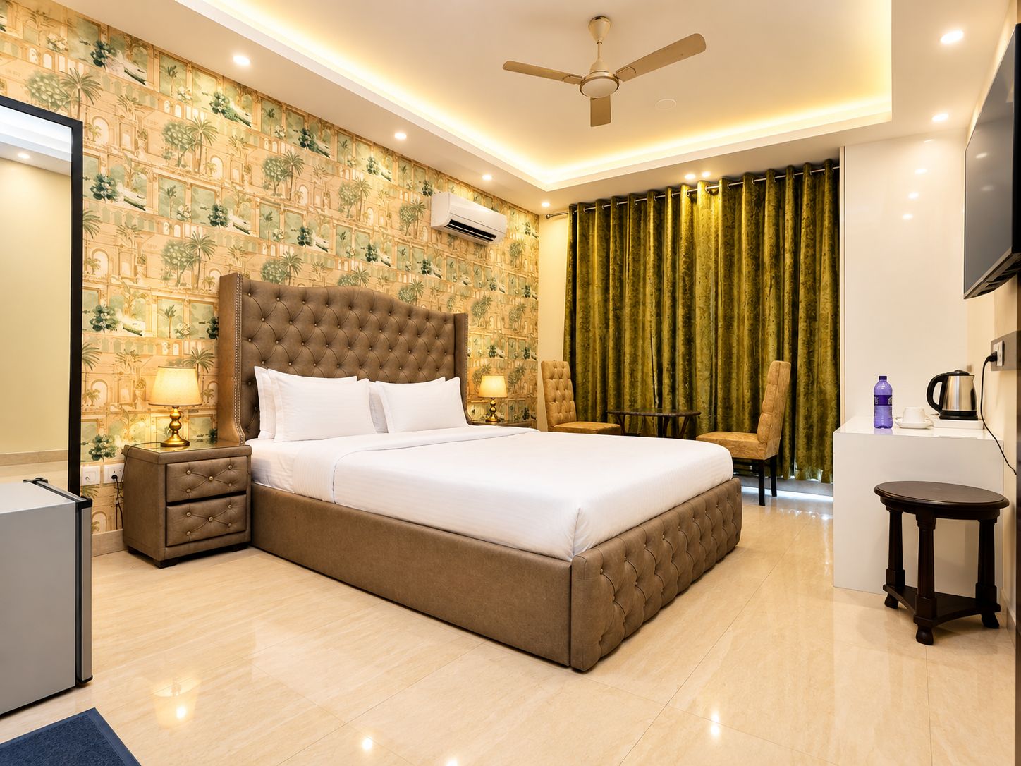 A hotel room with a large bed, a ceiling fan, a desk with a chair, and a television.