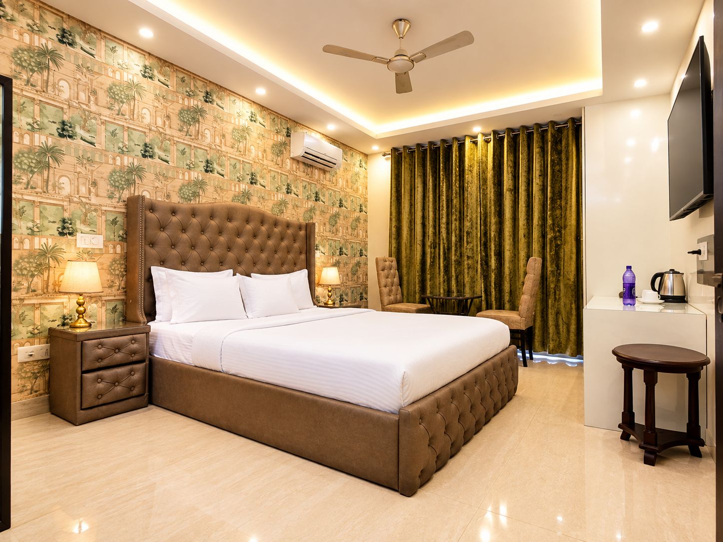 Une chambre d’hôtel avec un grand lit, un bureau, une chaise, une télévision et un ventilateur de plafond.