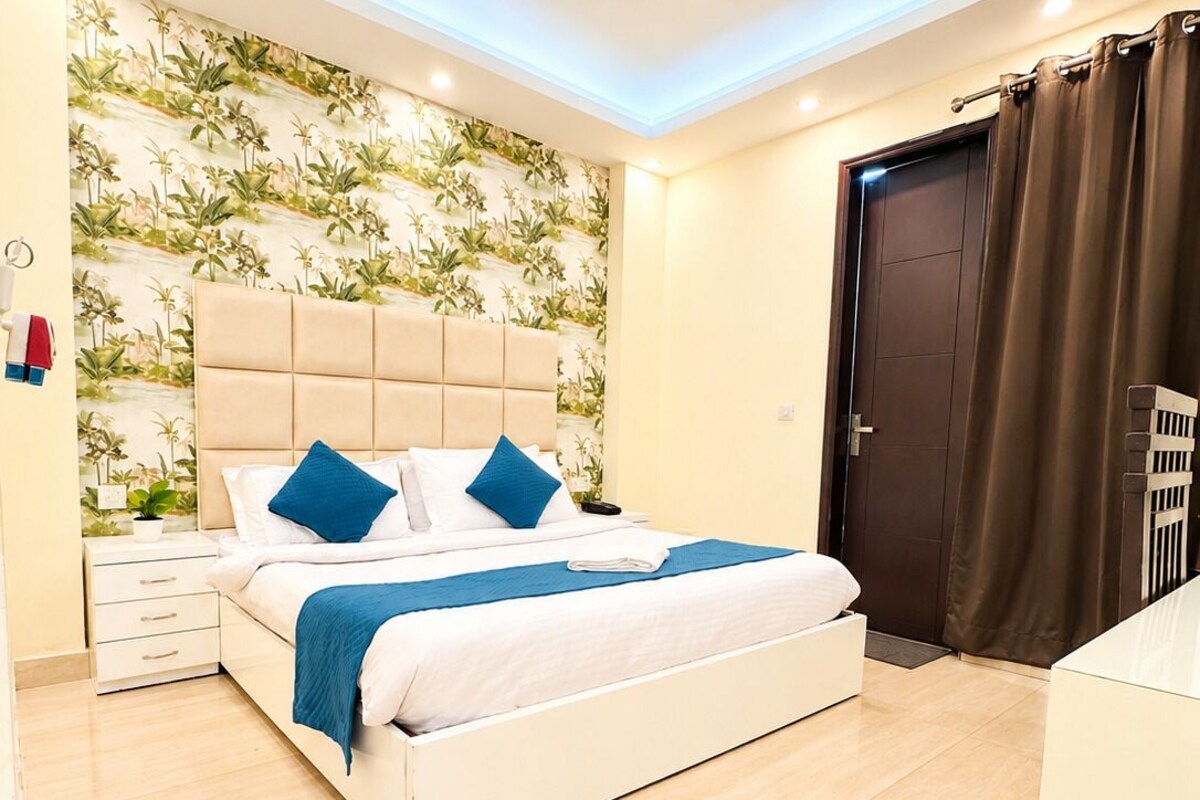 Un dormitorio moderno con cama, mesitas de noche, ventilador de techo y una puerta con cortinas.