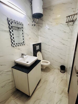 A bathroom with a white sink, a toilet, and a mirror. - Ambient Express Cr Park (New Delhi)