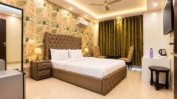 A hotel room with a large bed, a ceiling fan, a TV, and a minibar.