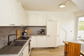 Une cuisine moderne avec des meubles blancs, un évier noir et une machine à café.