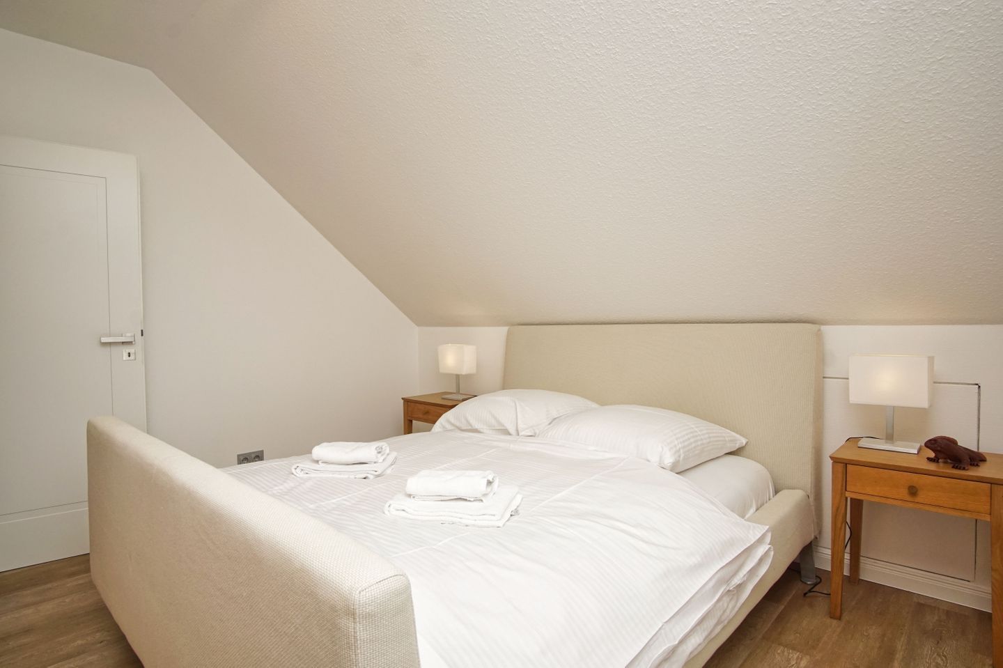 A neatly arranged bedroom with a bed, two bedside tables, and a door.