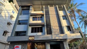 A modern building with a sign for 'Roots' at the entrance. - URBAN VIBES SERVICE STAY (Mangaluru)