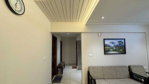 A living room with a sofa, a clock on the wall, and a painting. - URBAN VIBES SERVICE STAY (Mangaluru)