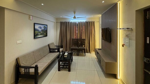 A modern living room with a sofa, coffee table, and TV. - URBAN VIBES SERVICE STAY (Mangaluru)