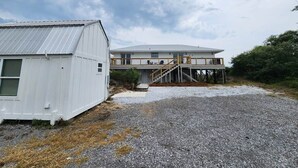 A two-story building with a covered outdoor area and a gravel driveway.