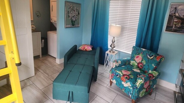 A compact bedroom with a bunk bed, a sofa, a chair, and a bedside table.