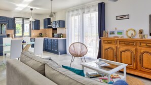 A modern living room with a sofa, a glass coffee table, and a dining area with a table and chairs.