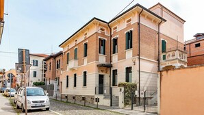 A row of traditional European-style buildings with a cobblestone street, parked cars, and a clear blue sky. - Spacious elegant central apartment, 10 minutes from Prato della Valle (Padova)