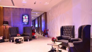 A modern lobby with leather armchairs, a coffee table, and a flat-screen TV displaying a welcome message. - Hotel Silvete (Lucknow)