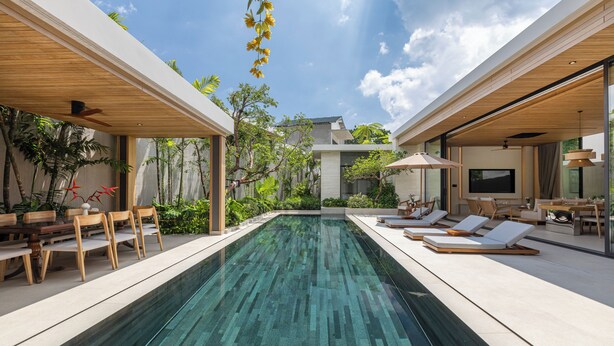 Un área de piscina moderna al aire libre con sillones de descanso y una zona de comedor.