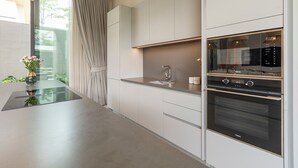 Una cocina moderna con horno empotrado, un lavamanos y una ventana con cortinas.