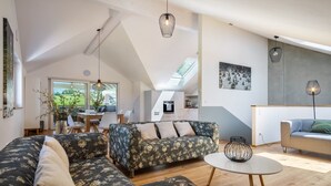 Amplia sala de estar con un sofá seccional, una mesa redonda de centro y una zona de comedor con mesa y sillas.